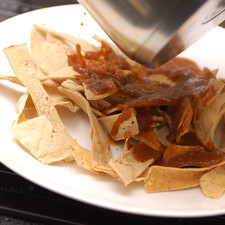 Servir tortillas tostadas en cada plato, bañar con salsa de chile pasilla y aderezar con cebolla picada, crema y queso desmenuzado.
