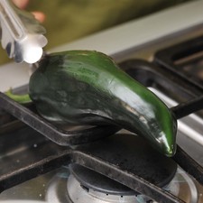 Asar los chiles sobre la hornilla de la estufa hasta que la piel esté negra.