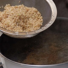 Poner a calentar el agua en una olla honda sobre la estufa. Cuando suelte el hervor, agregar la sal y la pimienta y mezclar. Añadir el arroz y el diente de ajo y esperar a que suelte el hervor, tapar, bajar el fuego y continuar cociendo durante 25 minutos. Escurrir el arroz sobre el fregadero.