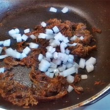 En un sartén, fríe el machacado y la cebolla.