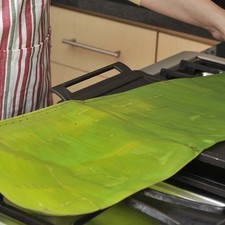 Calentar las hojas de plátano grandes sobre el comal para que se tornen flexibles.