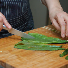 Hacer un corte por un lado de cada chile con un cuchillo para retirar las semillas y las venas. Cortar en rajas y reservar.