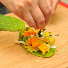 Agregar rajitas de flor de calabaza, chile jalapeño, cebolla y epazote. Sazonar con sal y poner encima otra penca de nopal para formar el sándwich.