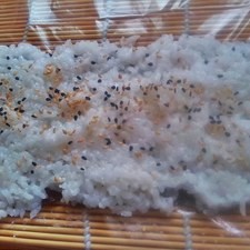 Coloca encima un poco de ajonjolí negro y beige y voltea el alga, ahora el lado brilloso o más liso estará “viendo” hacia ti.