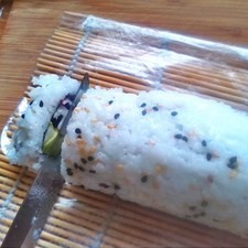 Humedece un cuchillo filoso en un vaso con agua y corta para formar rodajas de 1.5 cm. aprox., si es necesario tocar el makizushi, deberás hacerlo SIEMPRE CON LAS MANOS HÚMEDAS, de lo contrario el arroz se te pegará. Vuelve a humedecer el cuchillo y corta, repite esta operación hasta que termines con el makizushi.