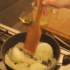 En una sartén verter un poco de aceite de oliva para dorar el arroz y la cebolla, meneando con frecuencia a que quede el grano transparente (no debe quemarse).