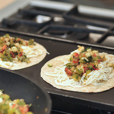 Cortar el queso en rebanaditas delgadas. Colocar una rebanada de queso sobre cada tortilla, agregar las verduras y doblar a la mitad en forma de quesadilla. Ponerlas en el comal a fuego lento y dejar que se derrita el queso y la tortilla quede crujiente y ligeramente dorada.