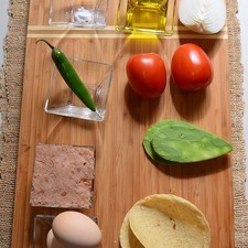 2 piezas de huevo aceite de oliva al gusto 1 pizca de bicarbonato de sodio sal al gusto 1/4 pieza de cebolla blanca 1 pieza de chile serrano 2 piezas de jitomate guaje 2 piezas de penca de nopal 4 piezas de tortilla de maíz
