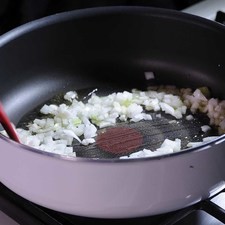 Para preparar el relleno, picar la cebolla, el ajo y las almendras previamente remojadas y peladas, la manzana y la pera en cuadros pequeños. Sofreír con un poco de aceite de oliva la cebolla picada hasta que se torne transparente durante 5 minutos.