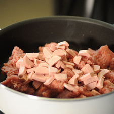 Agregar la carne y las salchichas al sartén a fuego lento durante 5 minutos, hasta que estén bien integrados.