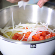 Agregar las verduras ya escurridas en el tazón del aderezo junto con el jitomate y la cebolla. Sazonar con sal y revolver bien.