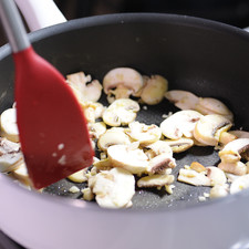 Mientras el soufflé se hornea, preparar una salsa de champiñones. Acitronar en una sartén abierta con aceite de oliva el ajo picado junto con los champiñones durante 3 minutos. Agregar las tres cucharadas de harina y menear fuertemente para que se dore durante 3 minutos.