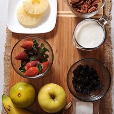 Desinfectante de verduras al gusto 2 cucharadas de azúcar blanca 1 taza de yogur natural 1/2 taza de uva pasa 1/2 taza de nuez picada 1 pieza de plátano 1 pieza de naranja 1 pieza de manzana 1 taza de fresas 2 rebanadas de piña en almíbar