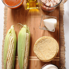 1/4 taza de aceite de oliva 1 taza de salsa roja picante 100 gramos de queso fresco 9 piezas de tortilla de maíz 1 taza de crema de leche de vaca 2 tazas de pavo desmenuzado 1/4 pieza de cebolla blanca 2 piezas de elote