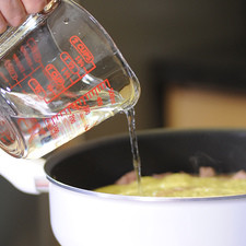 Agregar el resto del agua, revolver bien, tapar el sartén y cocer a fuego lento durante 25 minutos o hasta que la carne esté cocida.