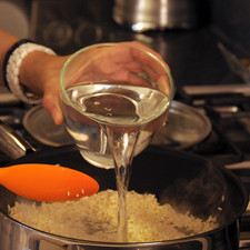 Poner a dorar el arroz en una sartén con un poco de aceite de oliva, moviendo con una cuchara de madera hasta que esté dorado pero no quemado. Agregar el agua y sazonar con 1 cucharadita de sal. Tapar y cocer a lumbre bajita durante 15 o 20 minutos hasta que el arroz esté cocido y se evapore toda el agua. Dejar enfriar.