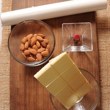 120 gramos de chocolate blanco para repostería 70 piezas de almendra papel encerado al gusto 10 gotas de colorante rojo vegetal