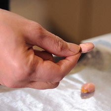 Agregar 10 gotas de colorante y revolver muy bien. Es importante no agregar más colorante para que el chocolate no se corte. Colocar papel encerado sobre una charola. Tomar una almendra de la parte más angosta y sumergirla en el chocolate y colocar en la charola y colocar una más de manera encontradas para formar un corazón.