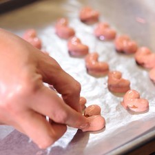 Añadir un poquito de chocolate con la ayuda de una cuchara pequeña en la base de las almendras para terminar de formar bien el corazón con el chocolate. Colocar la charola en el refrigerador durante 15 minutos.