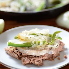 Servir la chuleta encima de una cama de frijoles refritos y acompañar con tortillas.