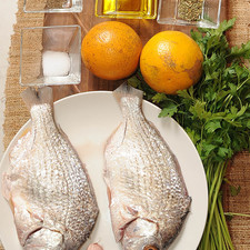 1/2 manojo de perejil fresco 1/4 taza de aceite de oliva papel aluminio al gusto 2 piezas de naranja 1/4 cucharita de orégano seco 1/2 cucharita de sal 1/4 cucharita de pimienta negra molida 1 diente de ajo 2 piezas de mojarra entera sin vísceras ni escamas