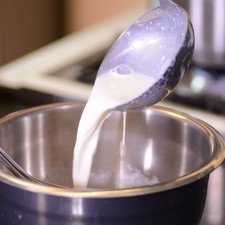 Tomar un cucharón de leche caliente y agregarla a las yemas batidas, mezclar vigorosamente de inmediato hasta integrar y atemperar.