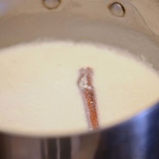 Mientras se cuece el arroz, poner a hervir la leche y la crema con la raja de canela en una olla honda a fuego lento, mezclar de vez en cuando.