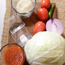 1 taza de arroz 1/2 pieza de cebolla morada 1 taza de salsa roja picante 1 pieza de chile serrano 1/2 cucharita de sal 1/4 cucharita de pimienta negra molida 4 ramas de hierbabuena fresca 3 piezas de jitomate guaje 500 gramos de carne molida de puerco 1 pieza de col o repollo