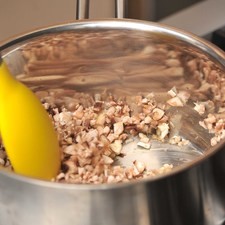 Para preparar la salsa de champiñones, acitronar en una sartén abierta con aceite de oliva 3 dientes de ajo junto con los champiñones finamente picados durante 3 minutos.