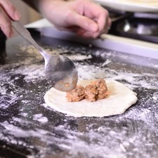 Colocar un poco de relleno en cada círculo de pasta y barnizar las orillas con la yema.