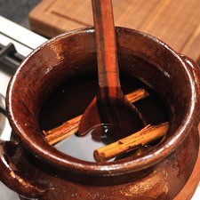 Calentar el agua en una olla de barro hasta que hierva, agregar el piloncillo, la canela y los clavos. Continuar calentando sin dejar de menear con la cuchara de madera hasta que el piloncillo se disuelva. Una vez que esté disuelto y suelte el hervor, dejar hervir durante cinco minutos.