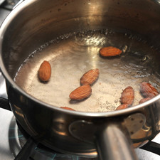 Poner a remojar las almendras de cinco a diez minutos en agua caliente. Escurrir y pelar.