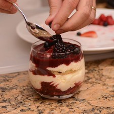 Añadir otra capa de crema, después coulis y adornar con frutos rojos enteros y otros partidos a la mitad.