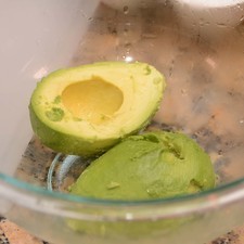 Para preparar el guacamole, cortar el aguacate en dos. Retirar la semilla y colocar la pulpa en un tazón.