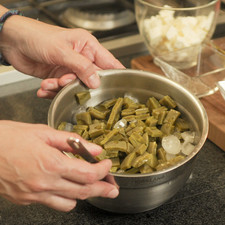 Picar cilantro y chile serrano, cortar cebolla en rodajas delgadas. Cortar nopales en cuadritos al igual que jitomate y queso. Calentar el agua en una olla honda. Cuando suelte el hervor, agregar 2 cucharitas de sal, una pizca de bicarbonato de sodio y los nopales. Cocer durante 8 minutos. Retirar del fuego, escurrir y refrescar en agua con hielo, escurrir.