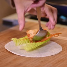 Calentar la tortilla de harina y colocar sobre ella una hoja de lechuga, un poco del pollo y tiras de jitomate.