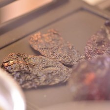 Tostar sobre el comal los chiles desvenados dándoles vuelta con la pinza para que queden asados pero no quemados.