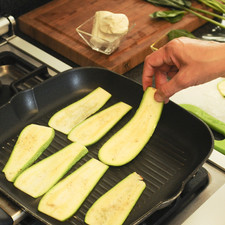 Lavar las calabacitas y cortarlas en rebanadas largas y delgadas. Untarlas con aceite de oliva por ambos lados utilizando una brocha y salpimentar. Poner a cocer sobre la parrilla durante 3 o 4 minutos de cada lado hasta que se tornen suaves y un poco doradas. Reservar.